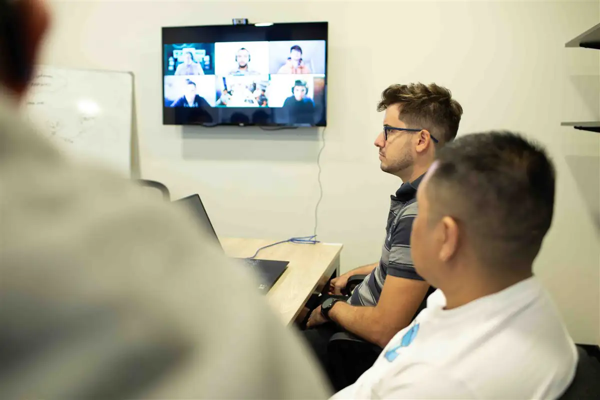 Una reunión en la oficina con parte del equipo conectado en la pantalla